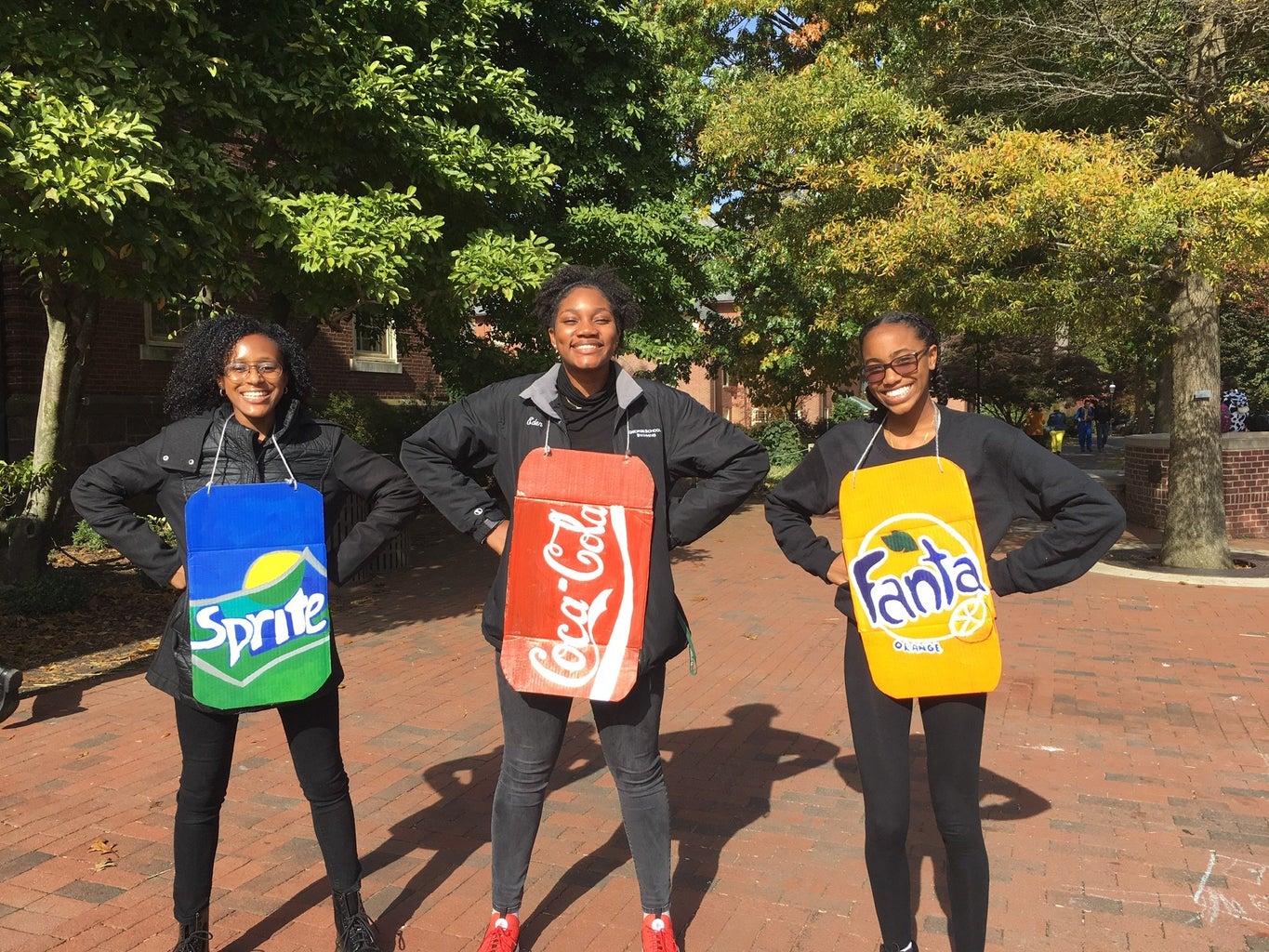 friends in homemade Halloween costumes: painted Coca-Cola, Sprite and Fanta logos onto pieces of cardboard