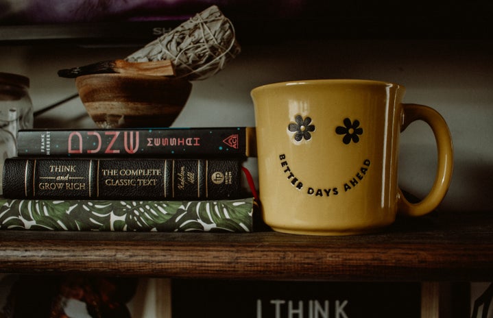 A yellow cup with text next to a pile of books