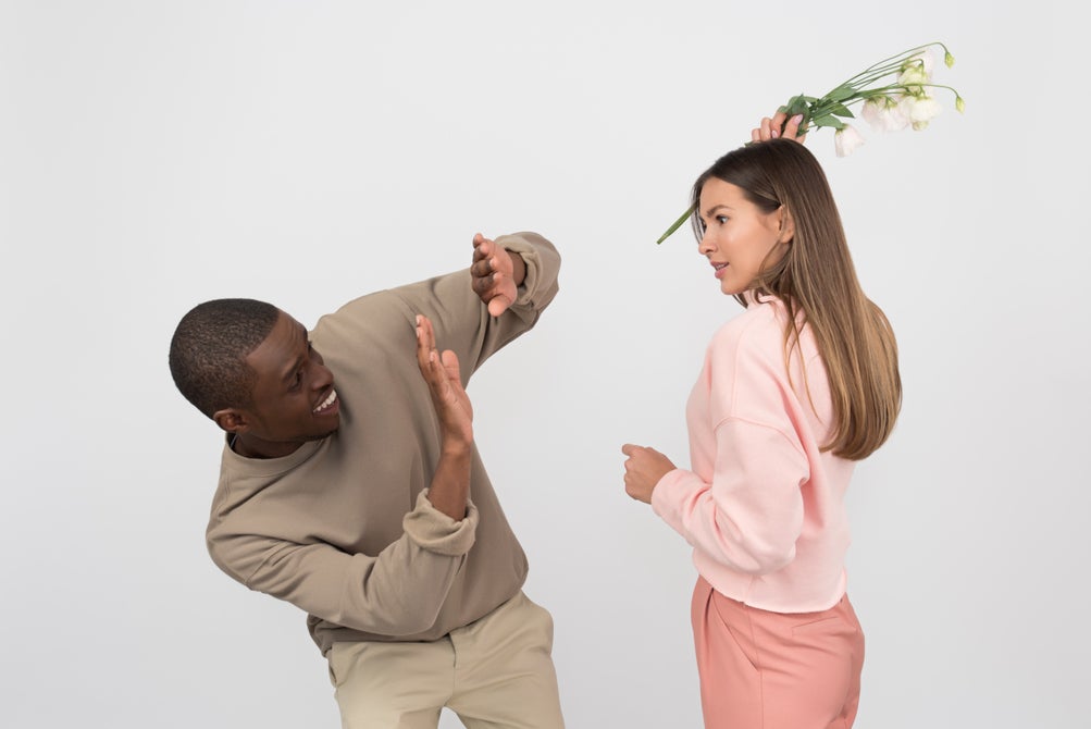 Woman angry at mad and brandishing flowers at him