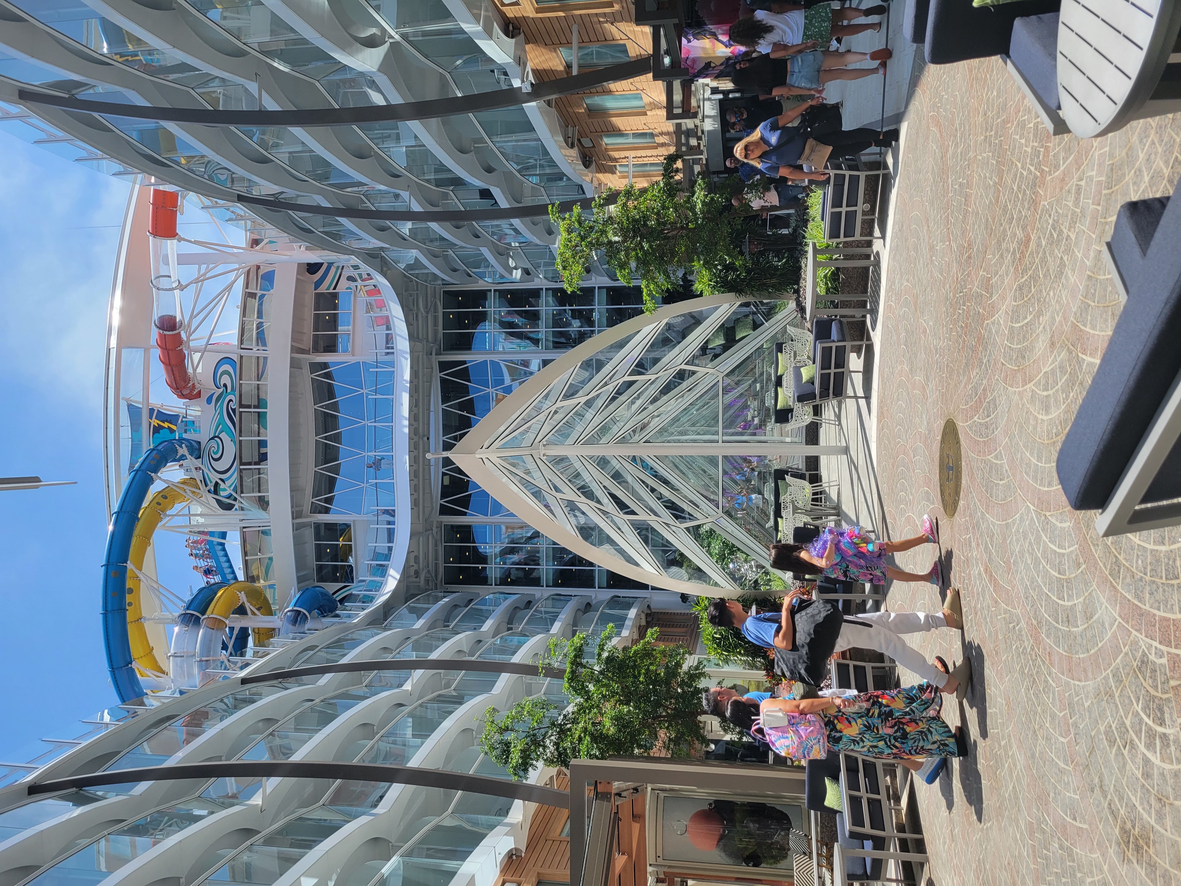 The outdoor glass atrium and wall of ivy/greenery of the Central Park neighborhood aboard the Utopia of the Seas