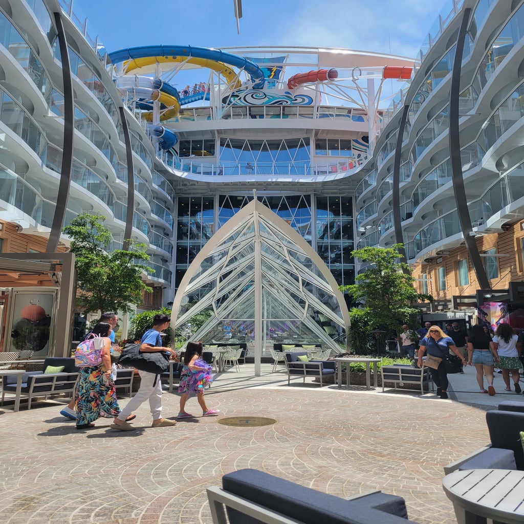 The outdoor glass atrium and wall of ivy/greenery of the Central Park neighborhood aboard the Utopia of the Seas