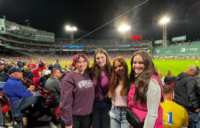 group of four girls dressed up in pink themed outfits at fenway park