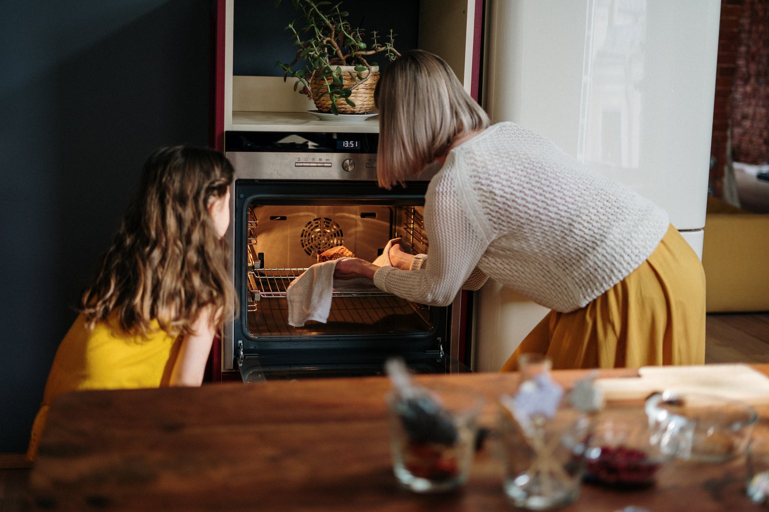 Woman and child taking food out of the oven.