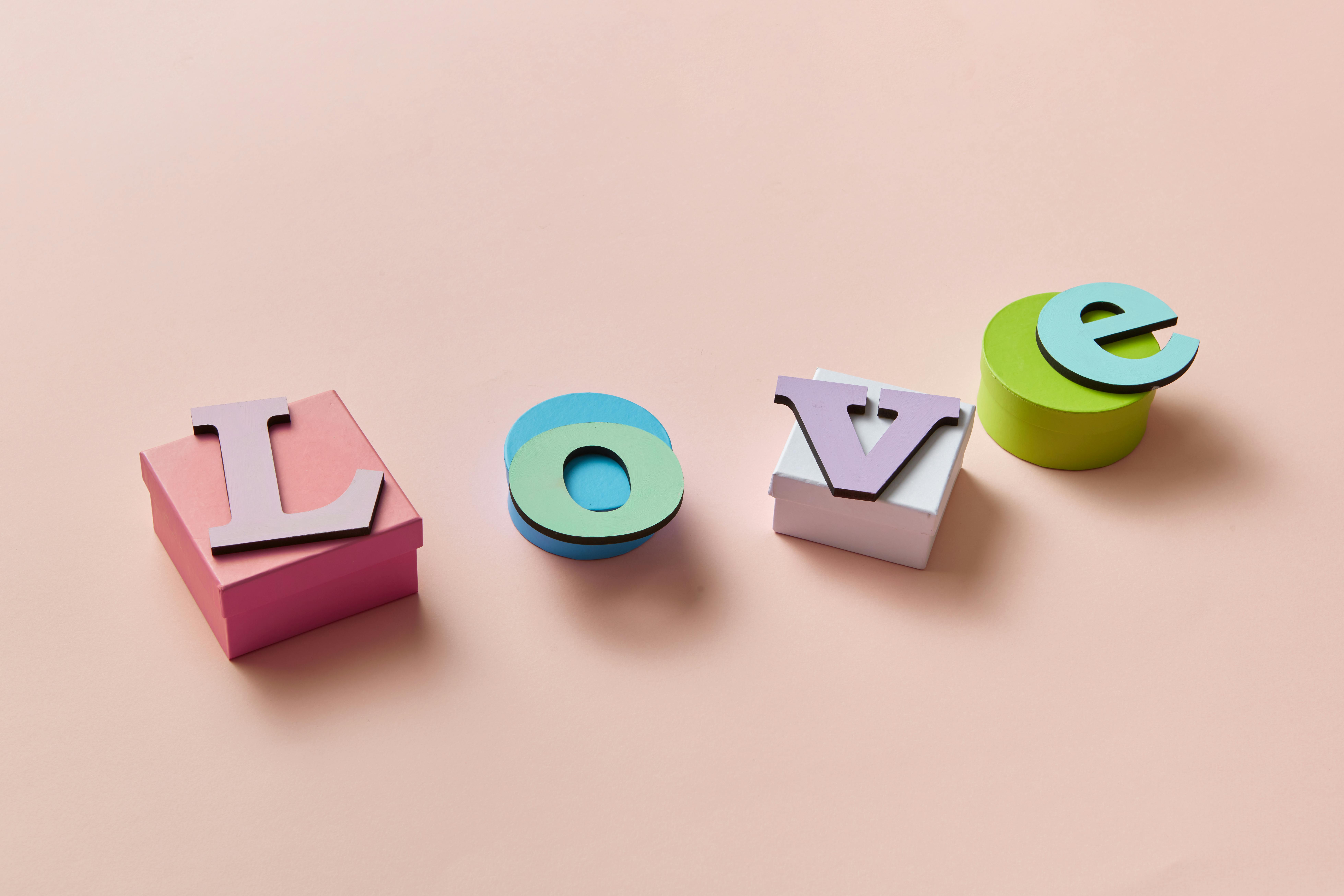 Letters spelling the word \"Love\" placed atop of colorful wooden boxes.