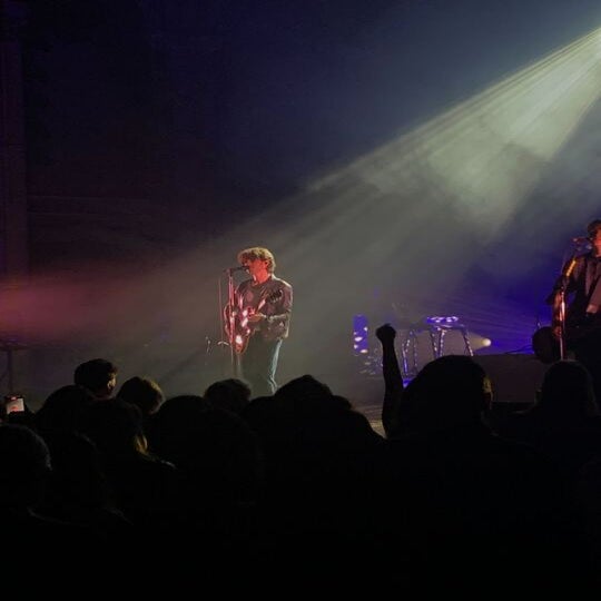 man singing onstage in the dark, inhaler