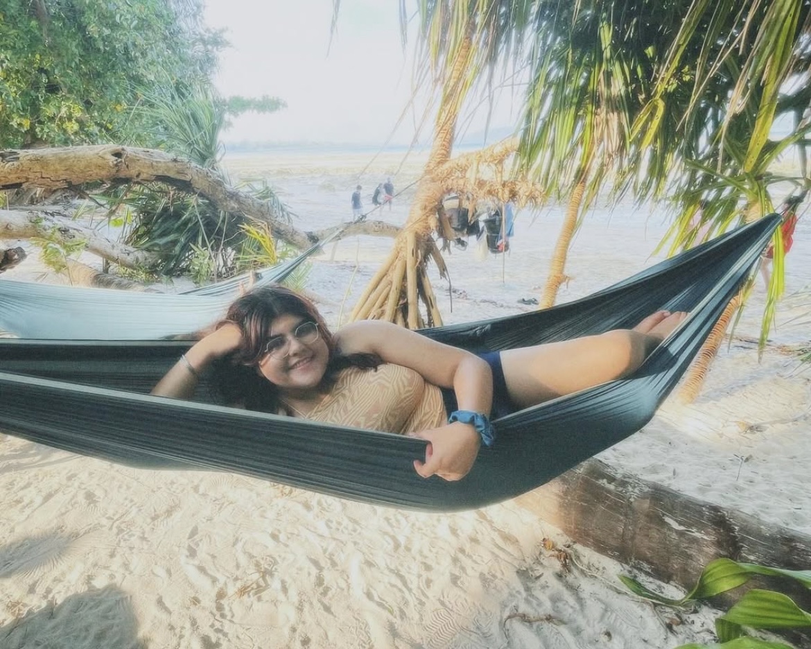 A girl (me) lying down, smiling in a hammock in Port Blair/Havelock Island.