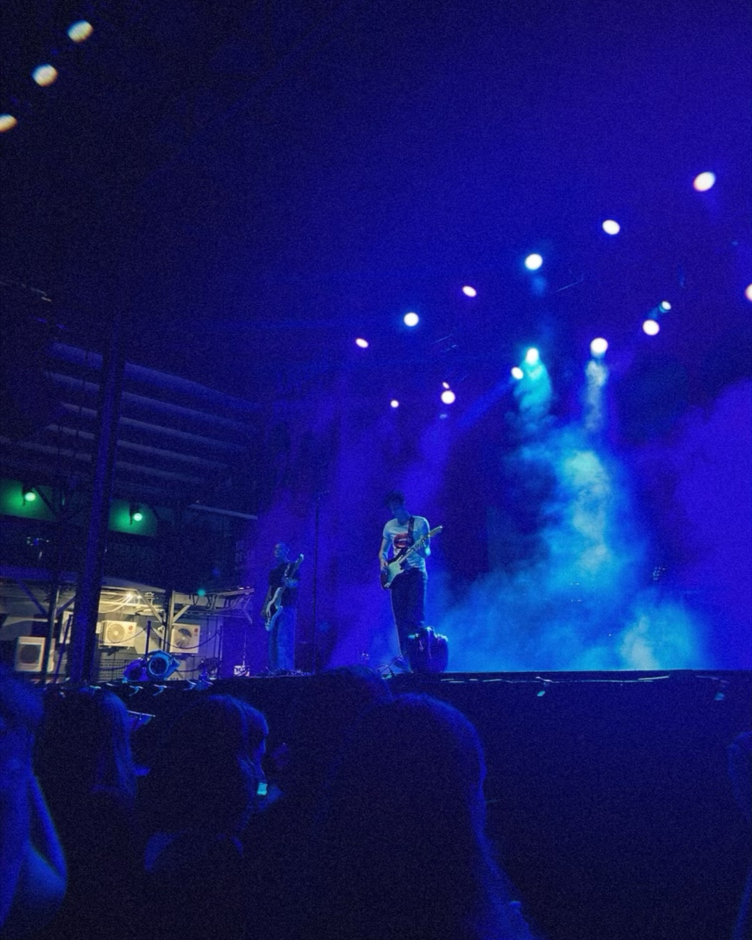 guy on stage playing guitar under blue lights