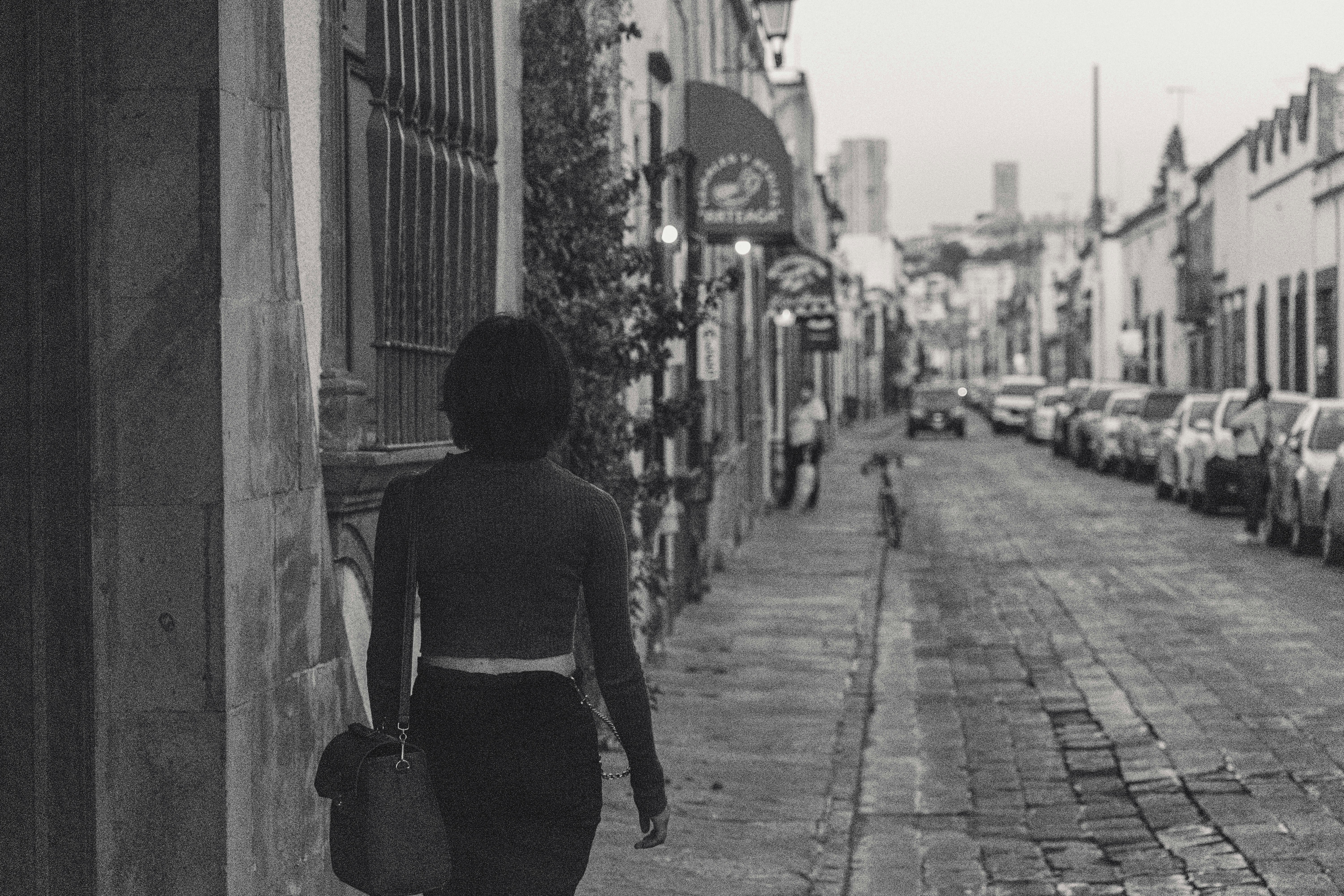 Woman walking alone on a car lined street