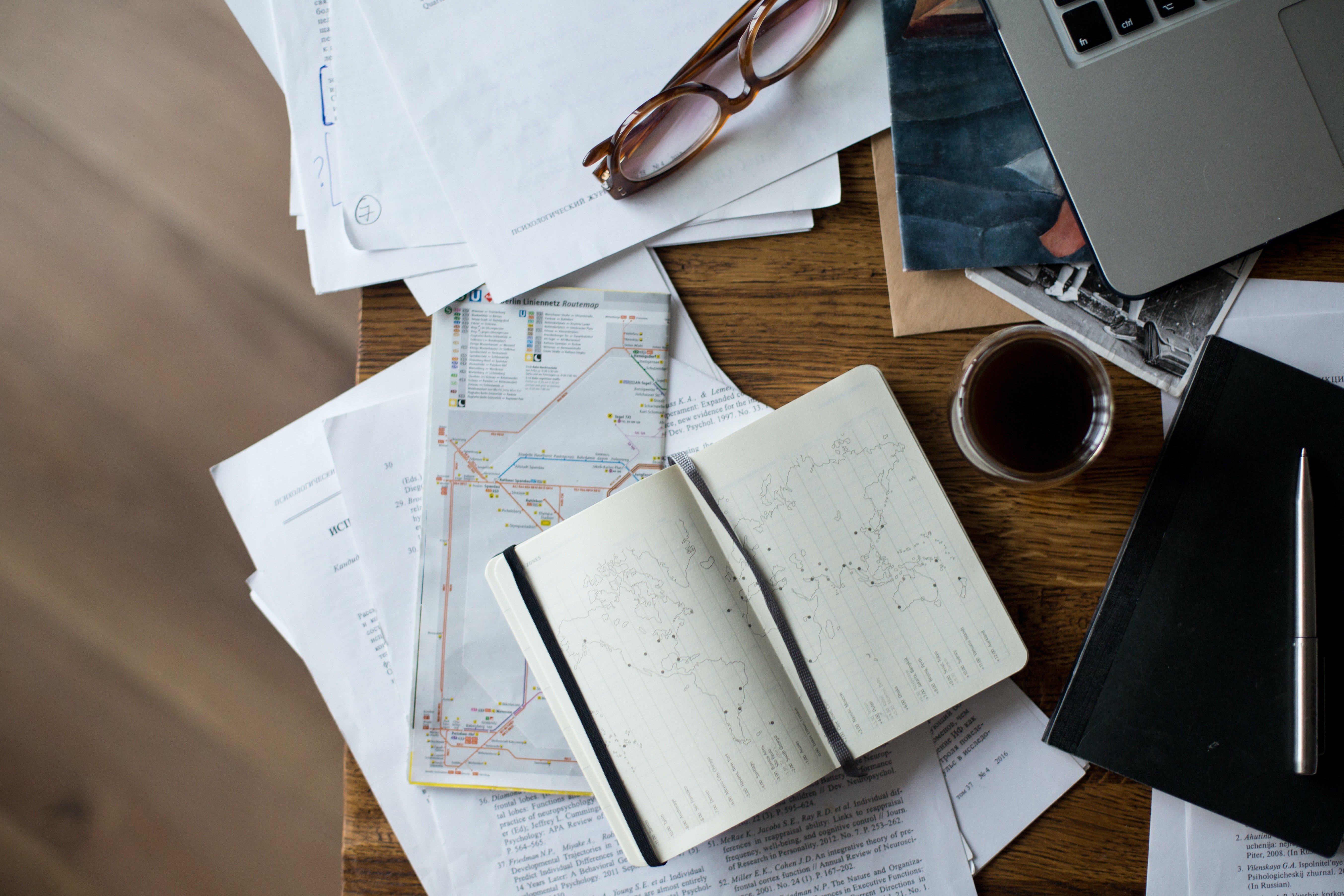 close up of desk with laptop, books, papers and coffee mug