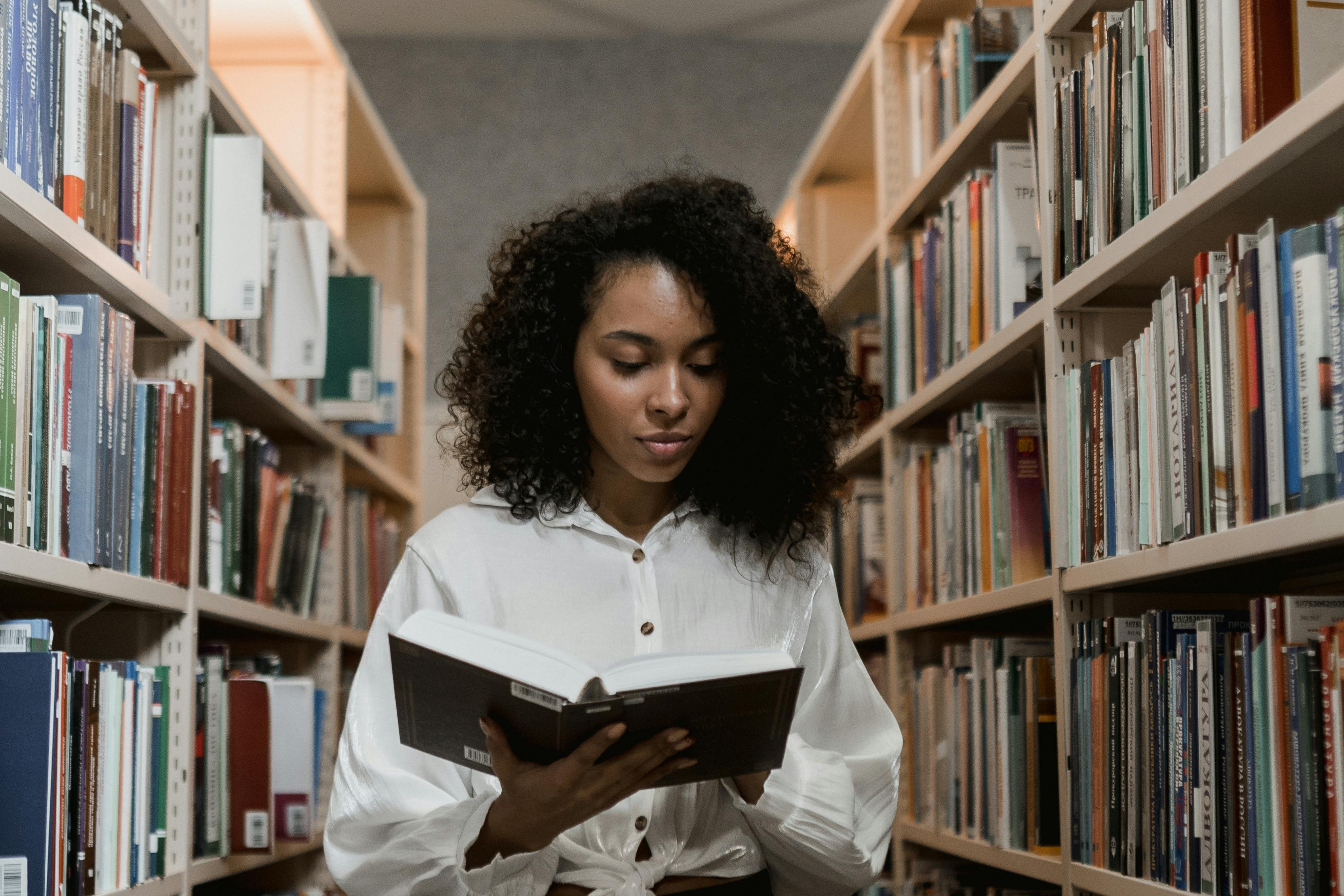 Girl in a library reading a book