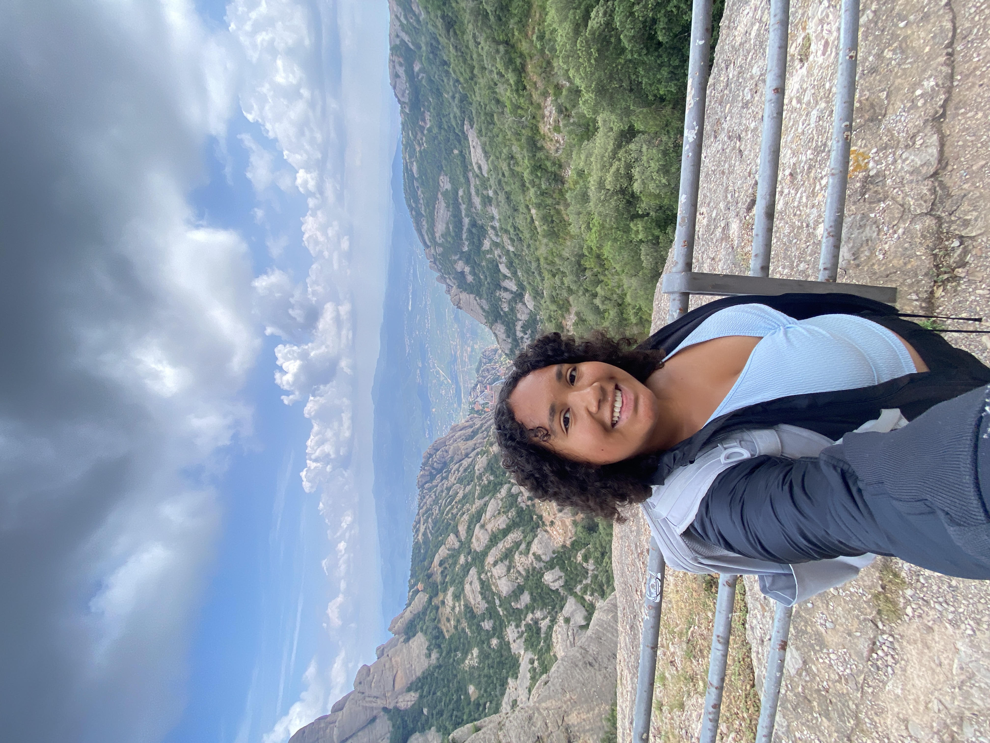 A woman on a trail with a mountainside behind her