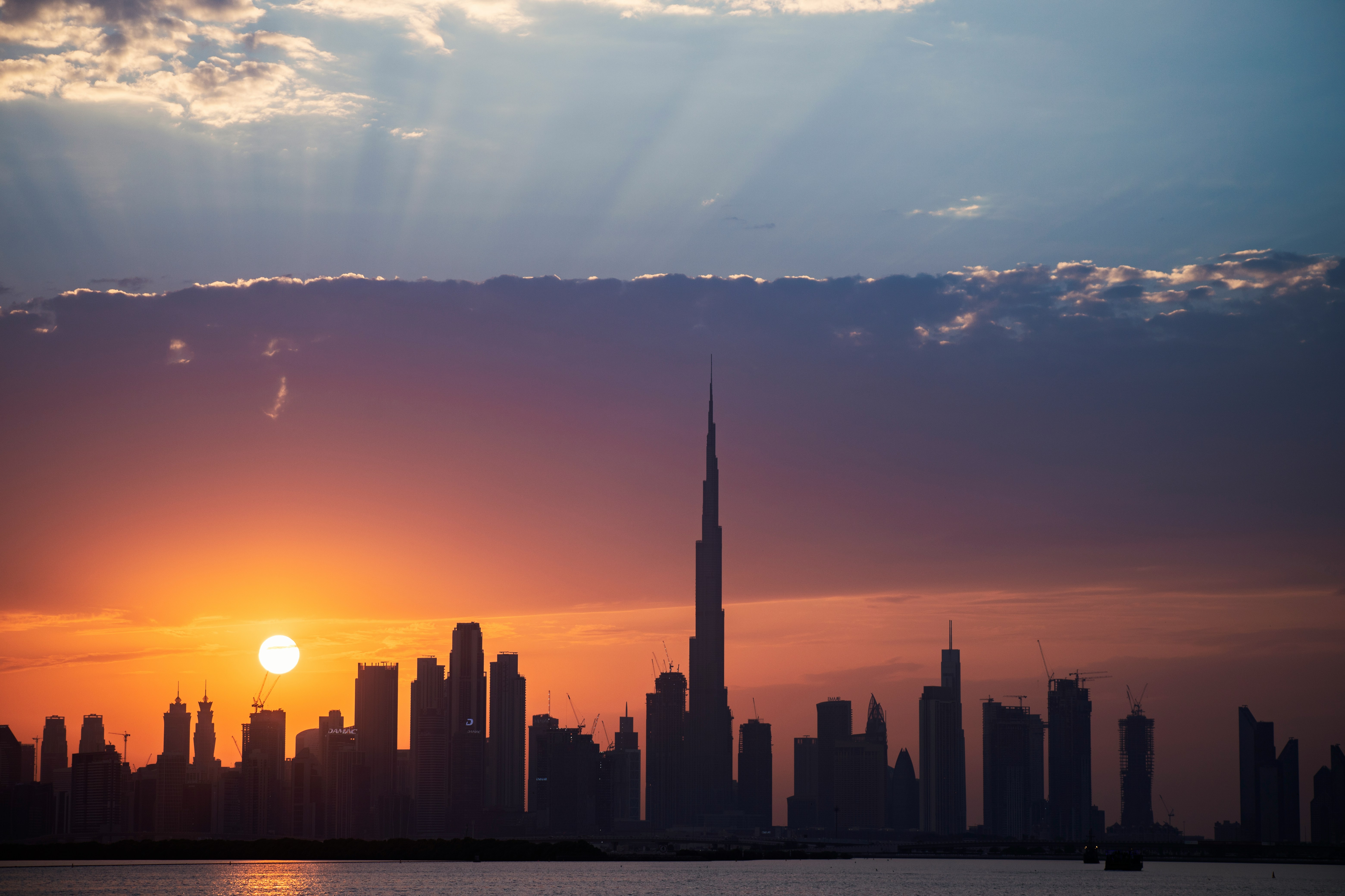 Dubai skyline at sunset, featuring the Burj Khalifa and surrounding skyscrapers against a warm evening sky.