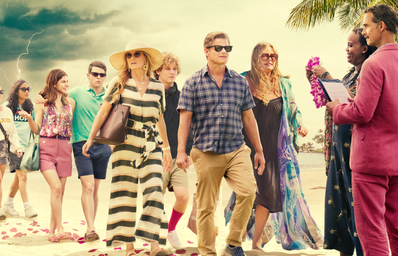 Group of people dressed for vacation walking on a beach.