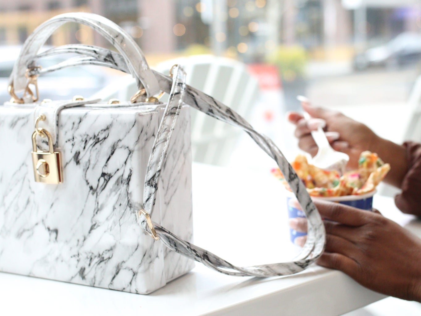 white purse with person eating dessert in the background
