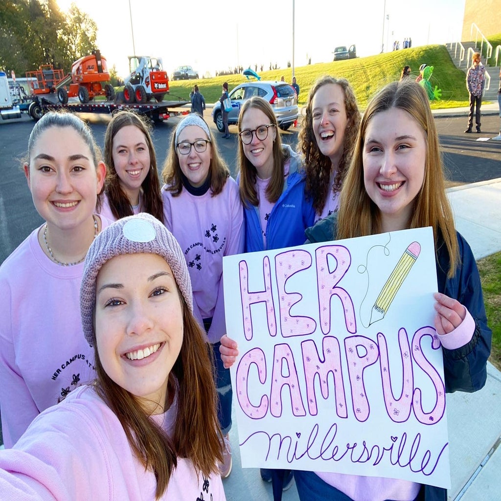 Her Campus Members holding up homecoming parade sign