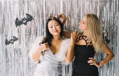 two girls dressed up in halloween costumes with a silver background