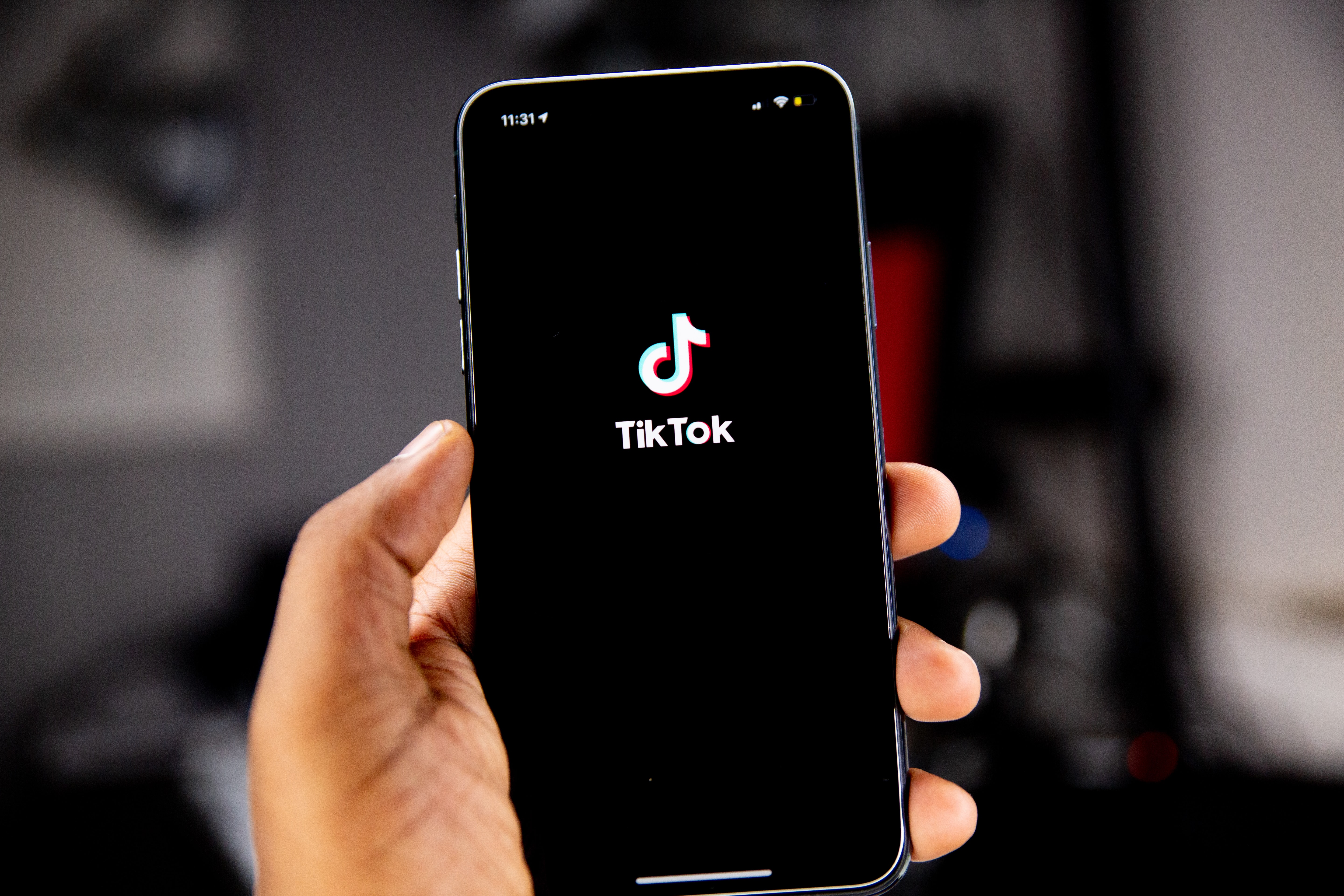 Picture of an iPhone in someone\'s hand with the TikTok homepage on the screen.