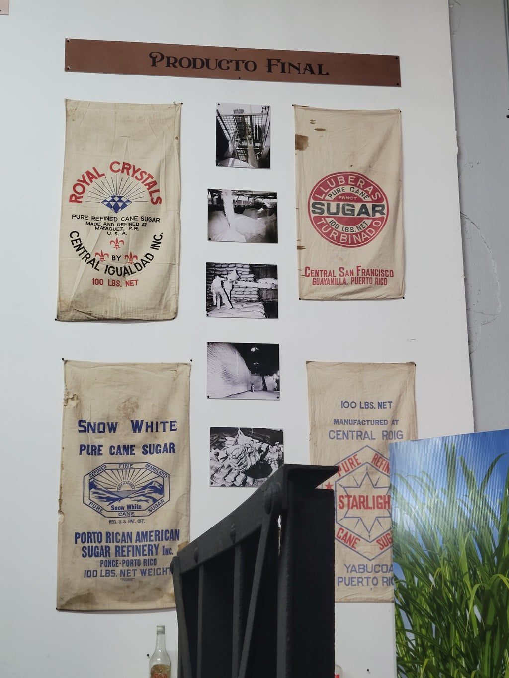 Sugar sacks from different places in Puerto Rico displayed on a wall.