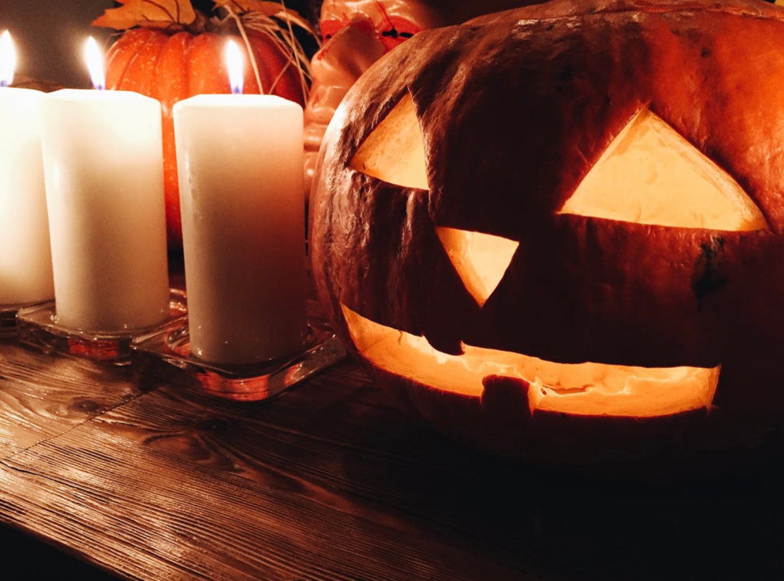 Carved pumpkin on table with candles by ?width=698&height=466&fit=crop&auto=webp&dpr=4