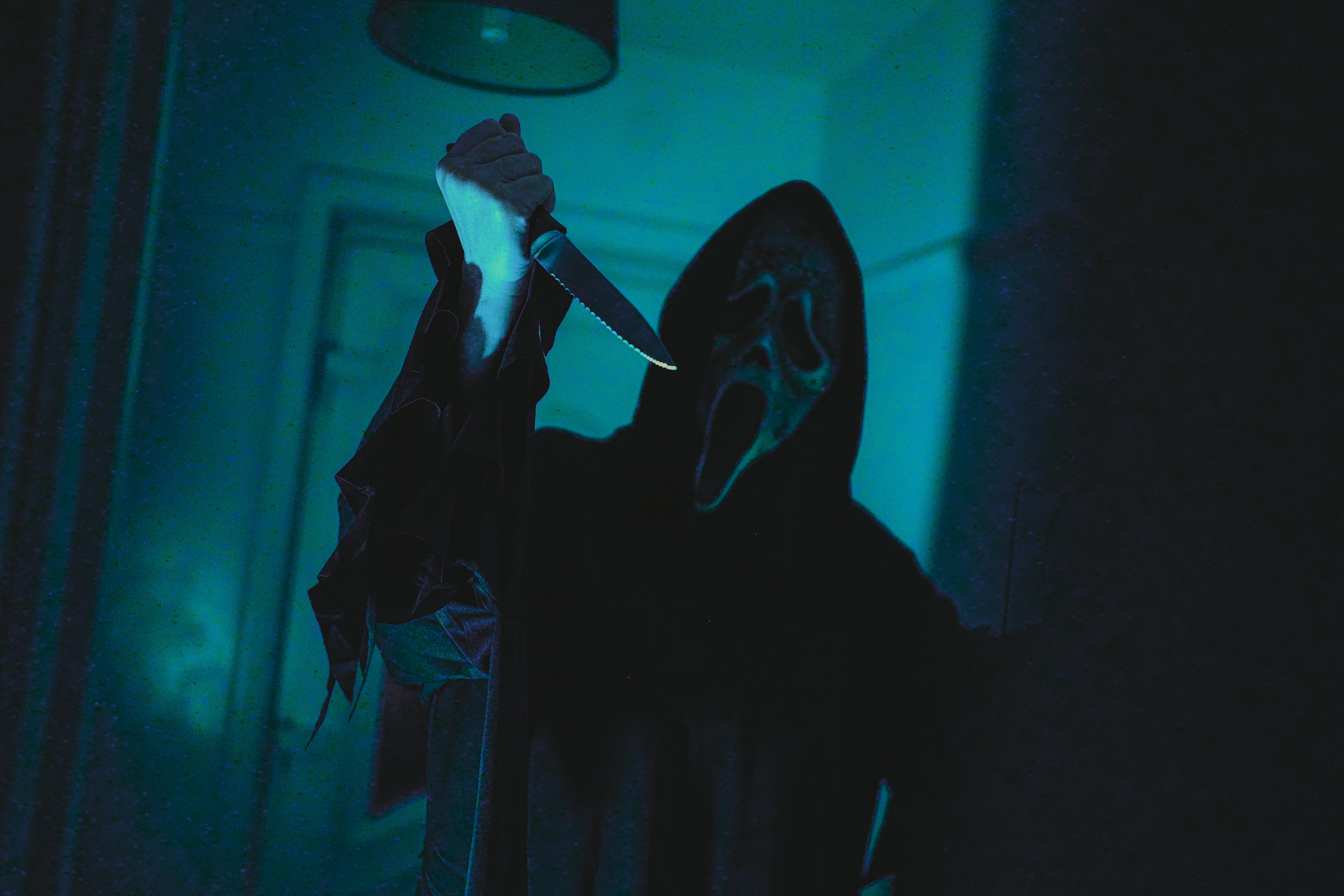 Ghostface holding up a knife with a blue background