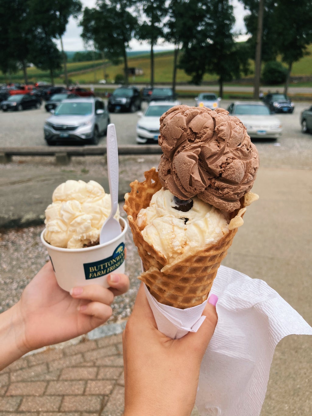 A cup and a waffle cone of ice cream outside in Connecticut.