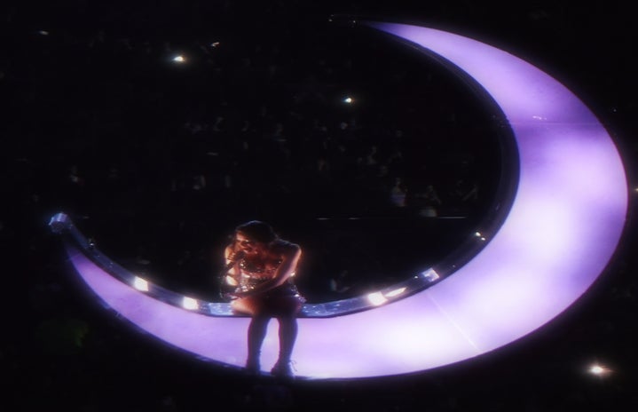Singer Olivia Rodrigo sits on a large purple moon while singing above the audience at Toronto\'s Scotiabank Arena.