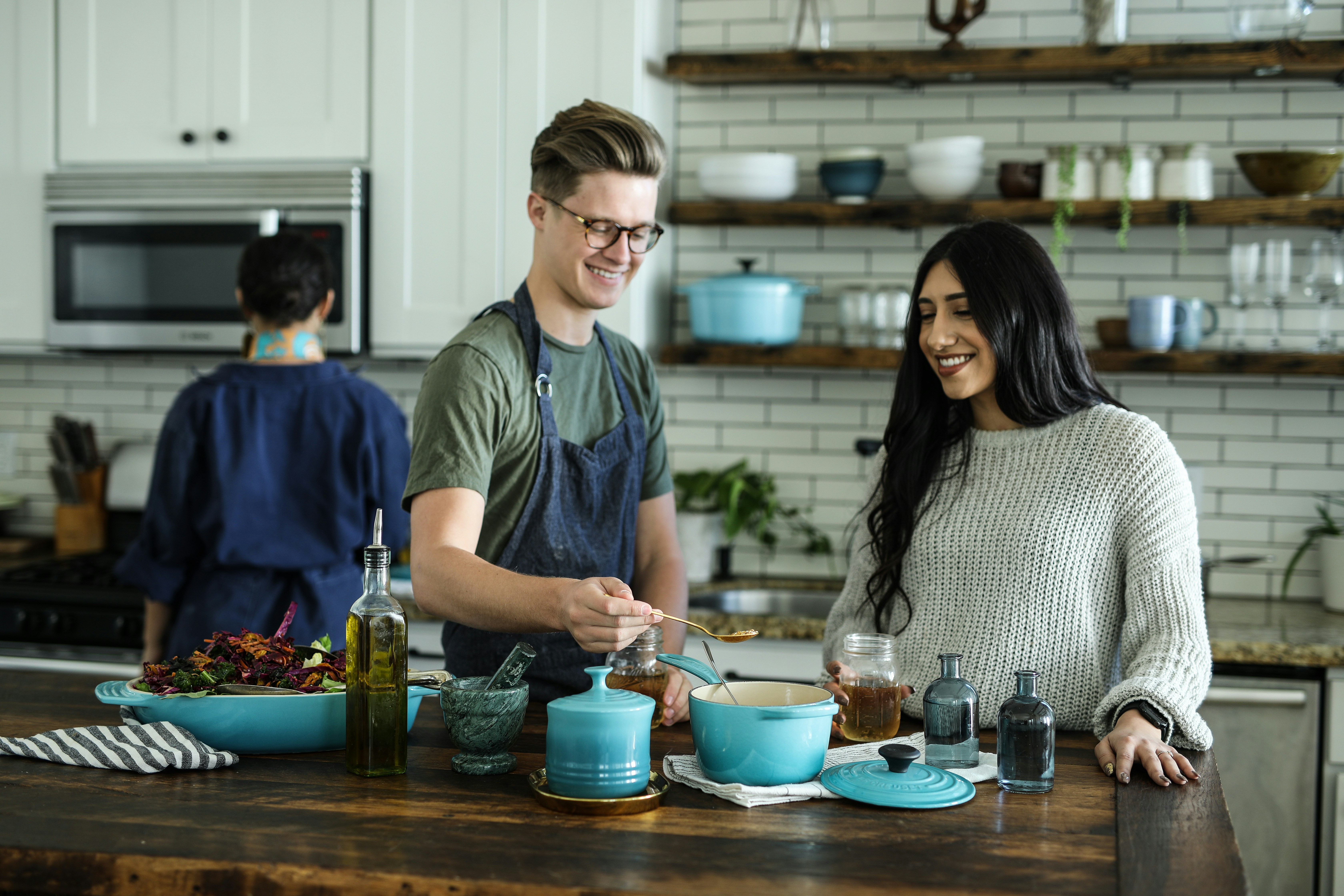 Smiling man standing and mixing food mix near woman in kitchen area of a house