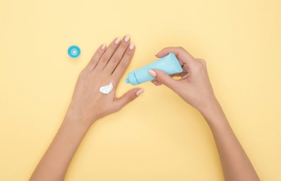 Woman\'s hands applying sunscreen amongst a yellow background