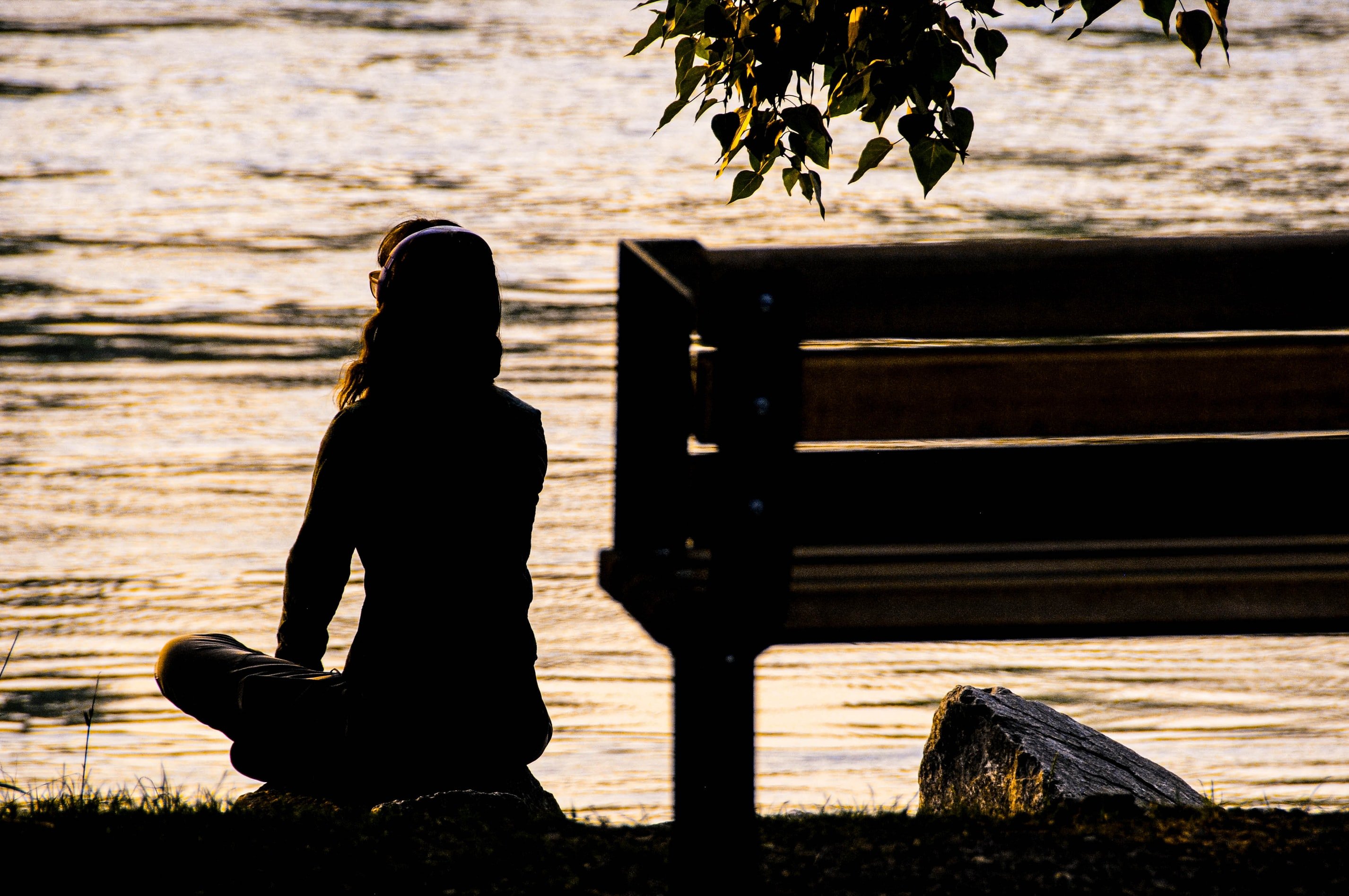 Woman sitting by the river at sunset