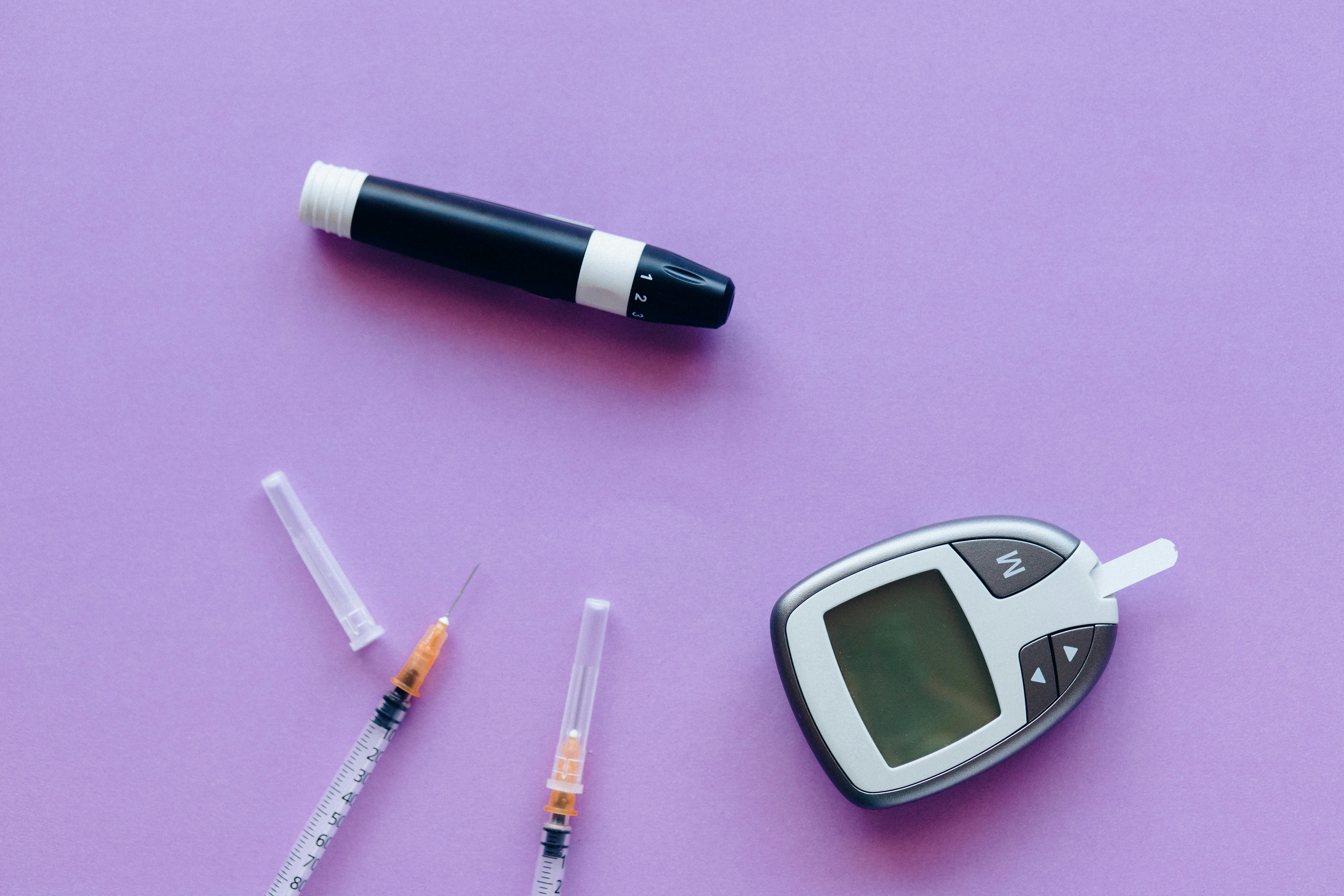 Diabetic kit and insulin over a purple surface.