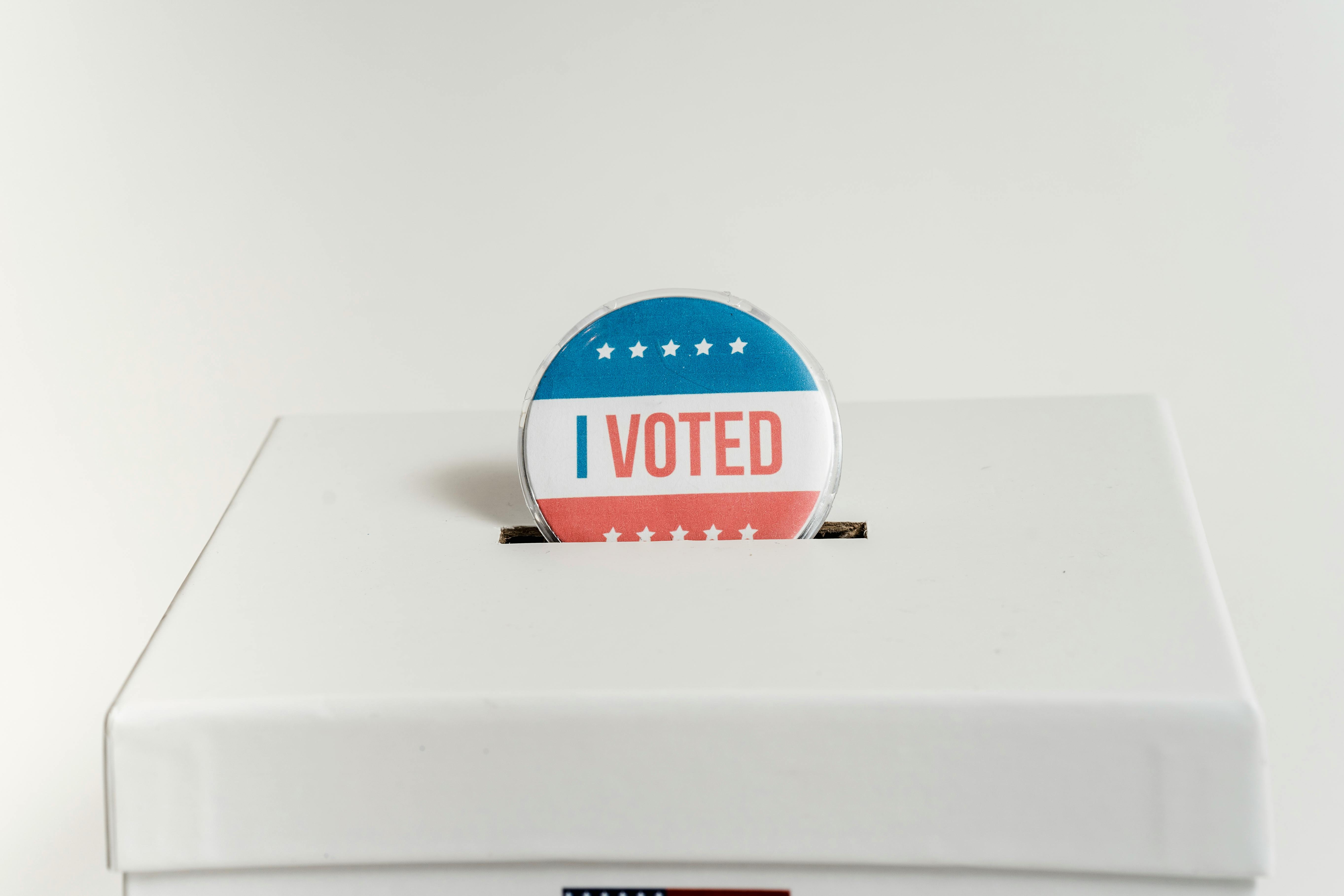 A badge that says \"I voted\" placed into a ballot box.