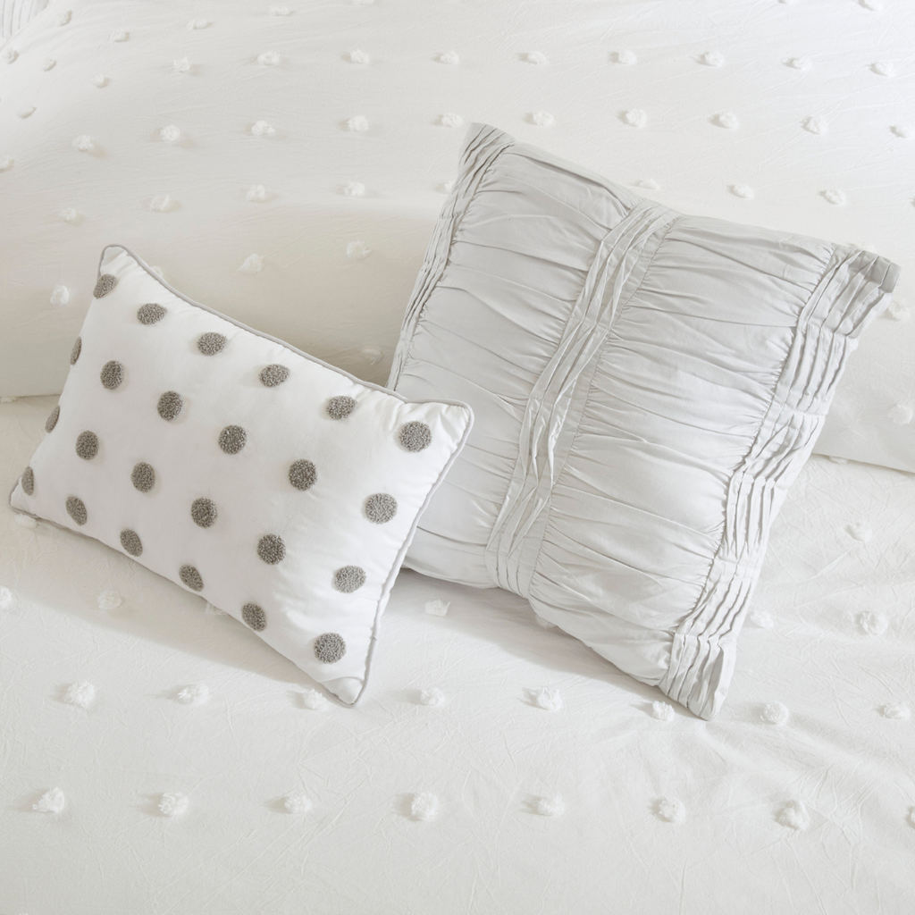 two white throw pillows on top of a white comforter with embroidered polka dots