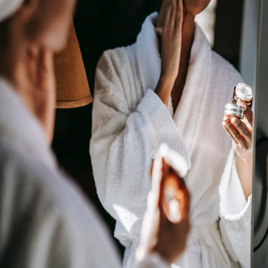 woman applying face cream in front of the mirror
