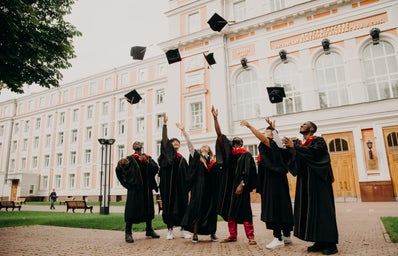 students in black robes tossing graduation caps