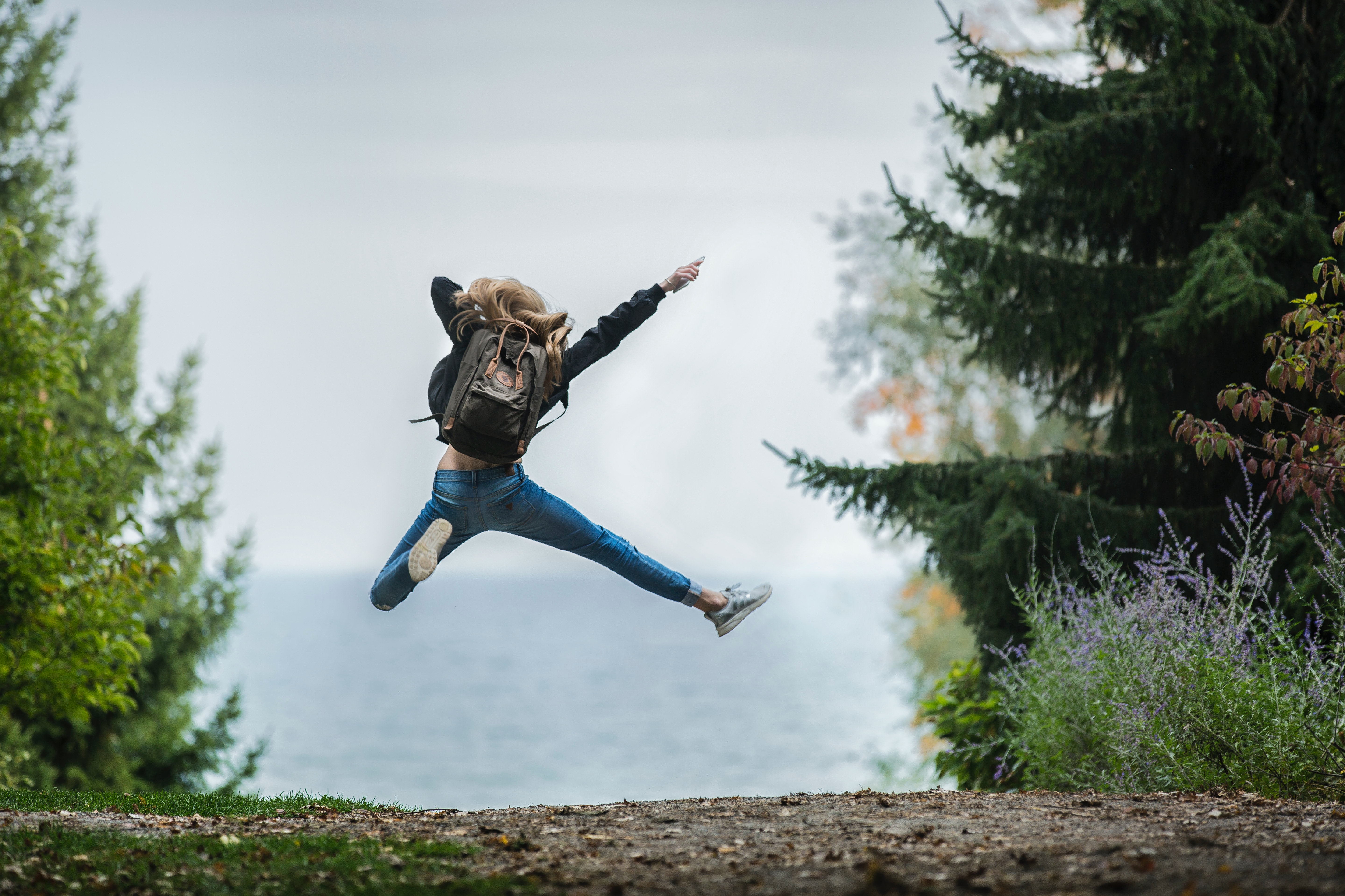 Woman jumping with green backpack