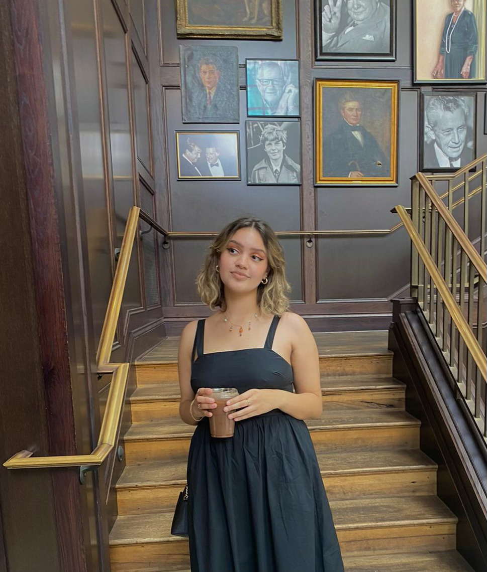 Isabella Sodre in a black dress holding an iced coffee