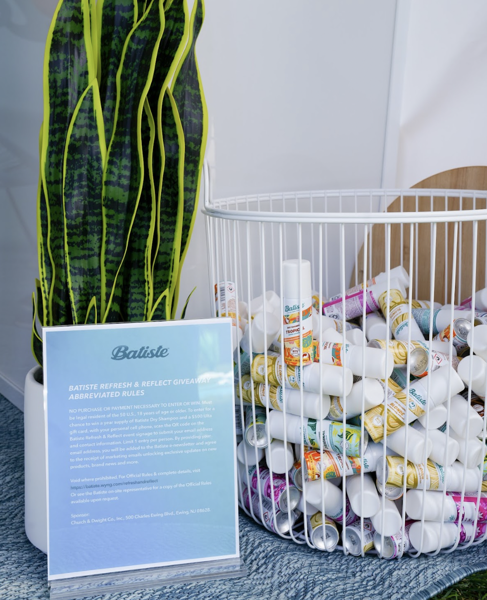A basket of Batiste dry shampoo next to a snake plant.