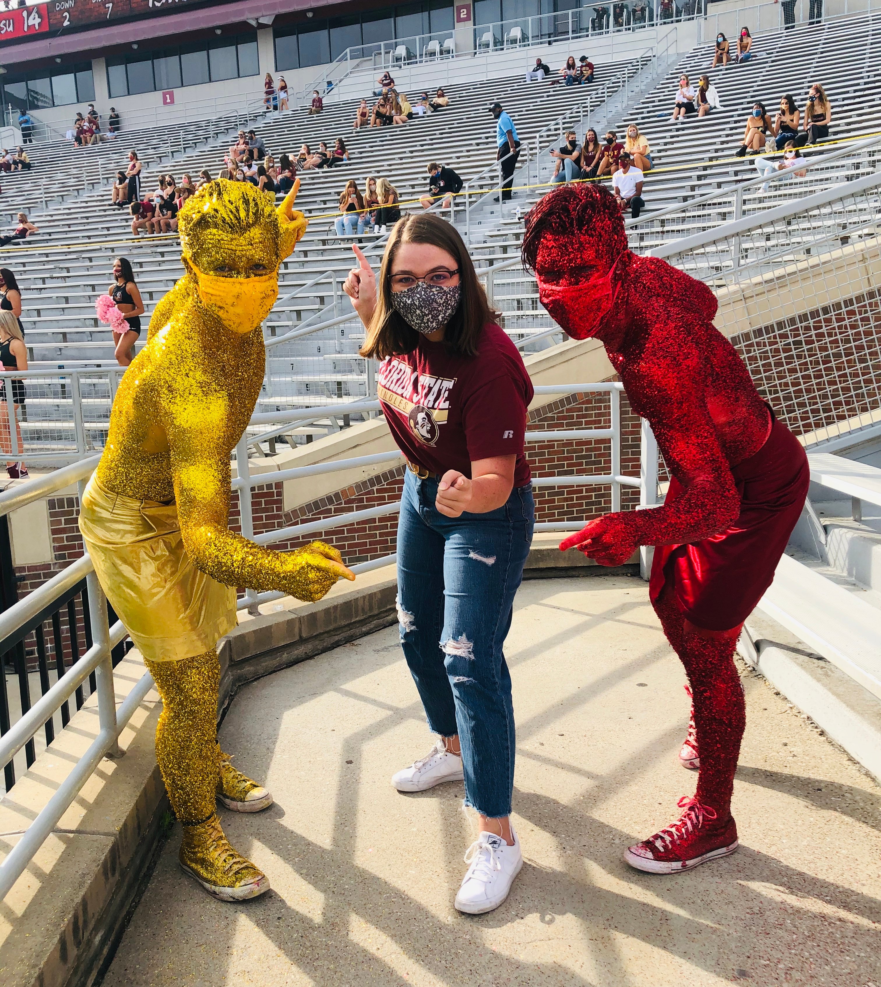 a girl standing between two guys who are covered in gold and garnet glitter