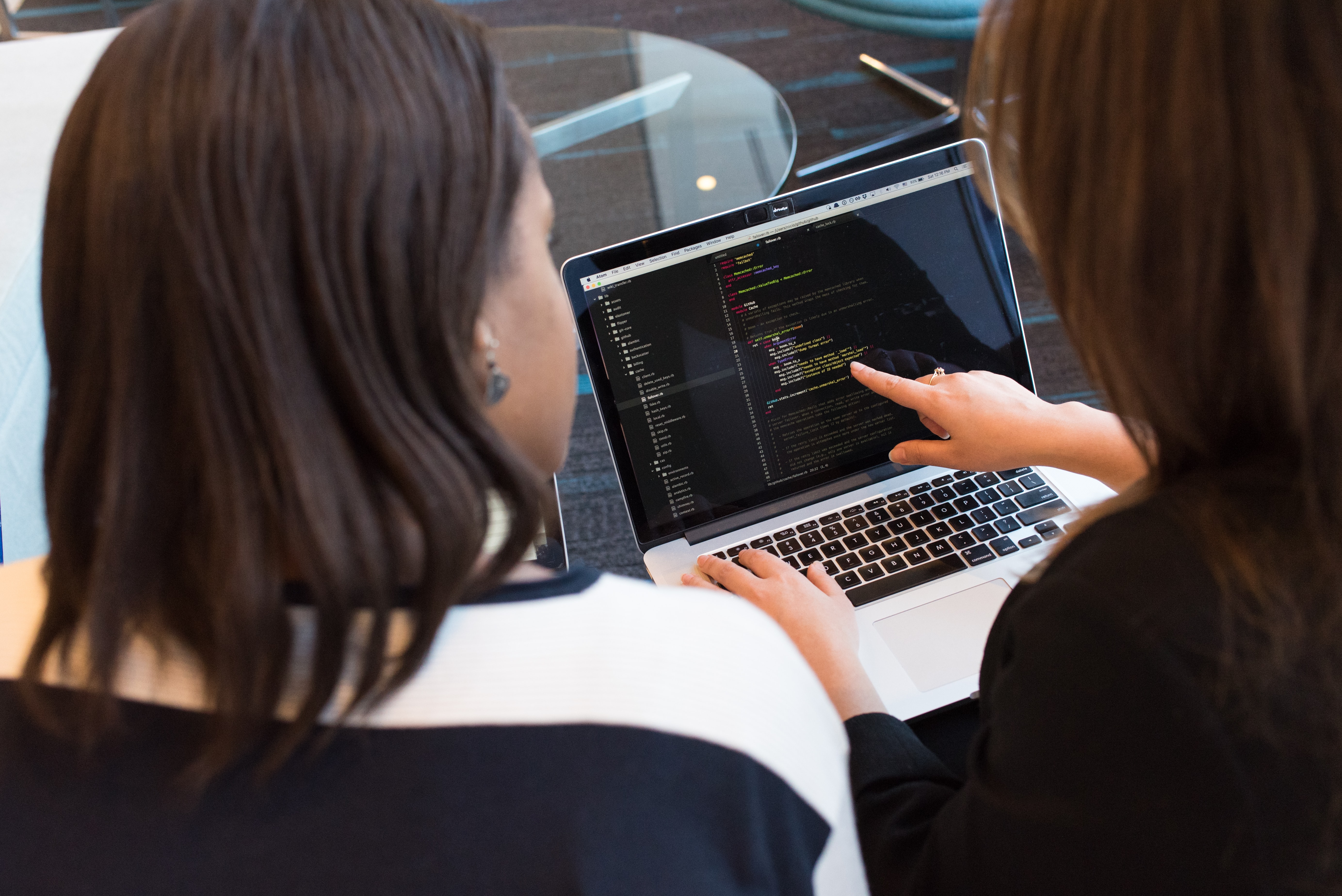 Two women looking at computer with code