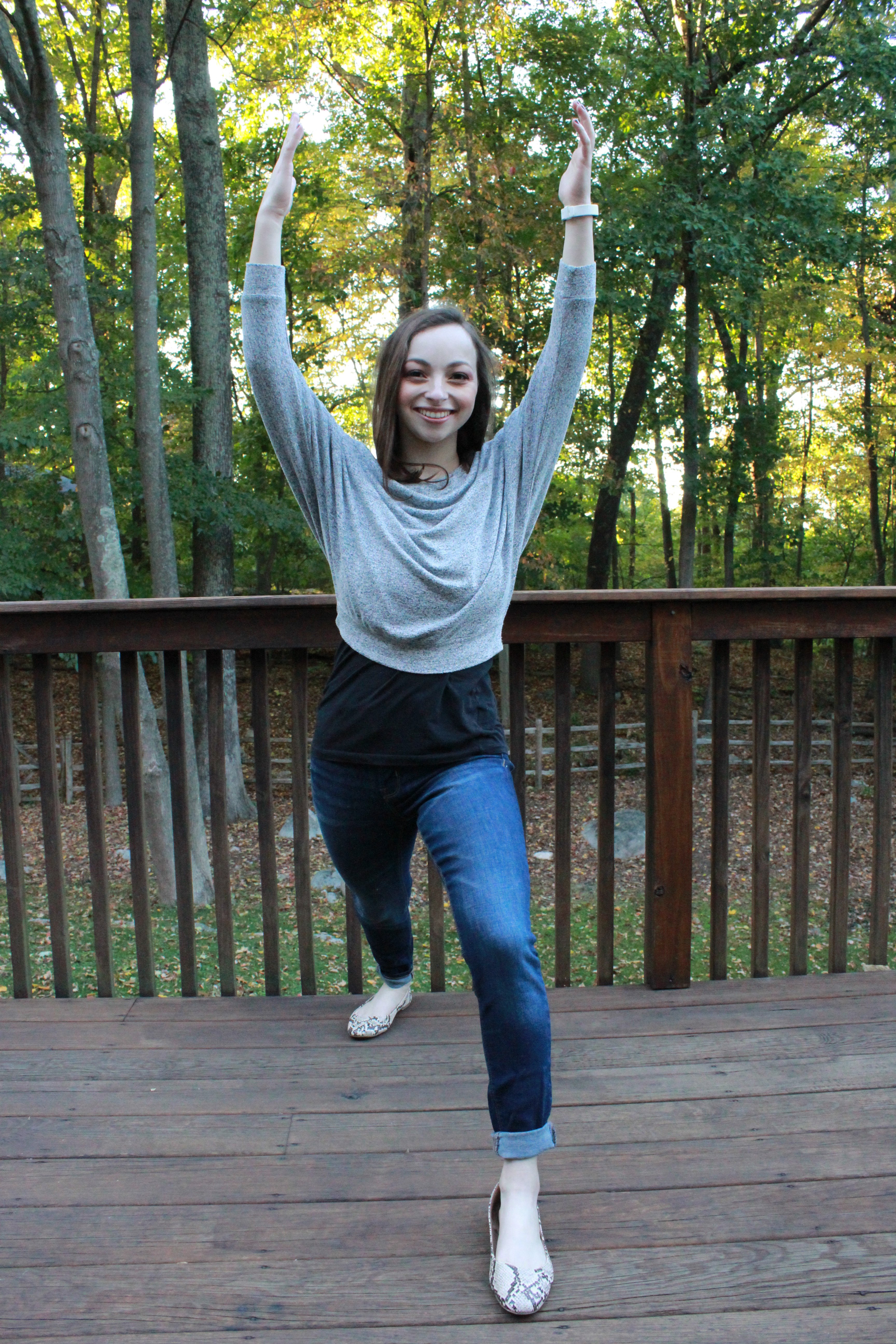 Camryn Chernick demonstrating Warrior 1 from the front view in jeans to show various yoga poses can be done in tighter clothing.