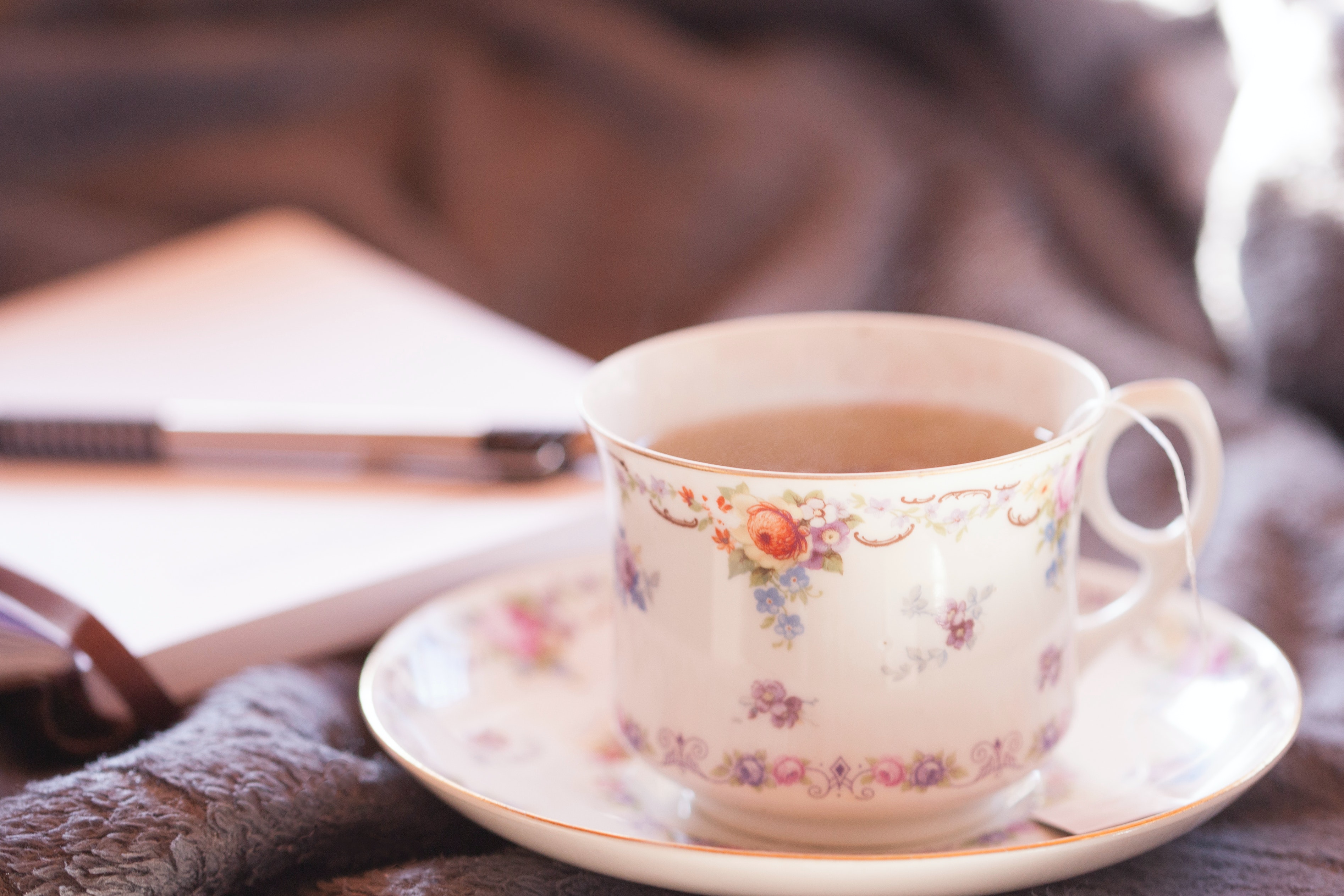 Cup of tea with notebook and pen in background