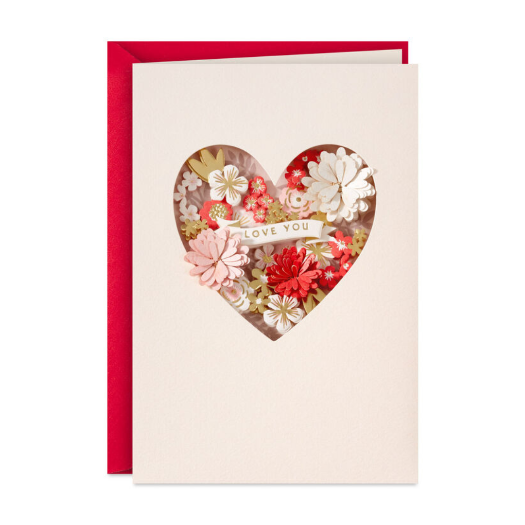 Greeting card with a cut-out heart revealing delicate red, pink, and white paper flowers and a \