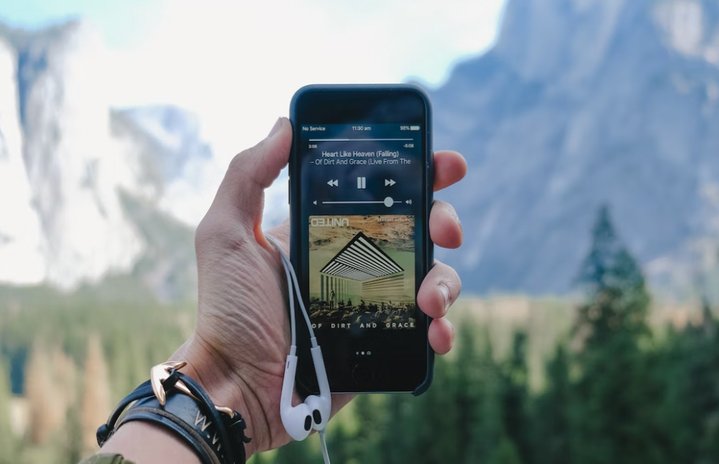 person holding phone showing music with a nature setting (I typed in music and headphones)