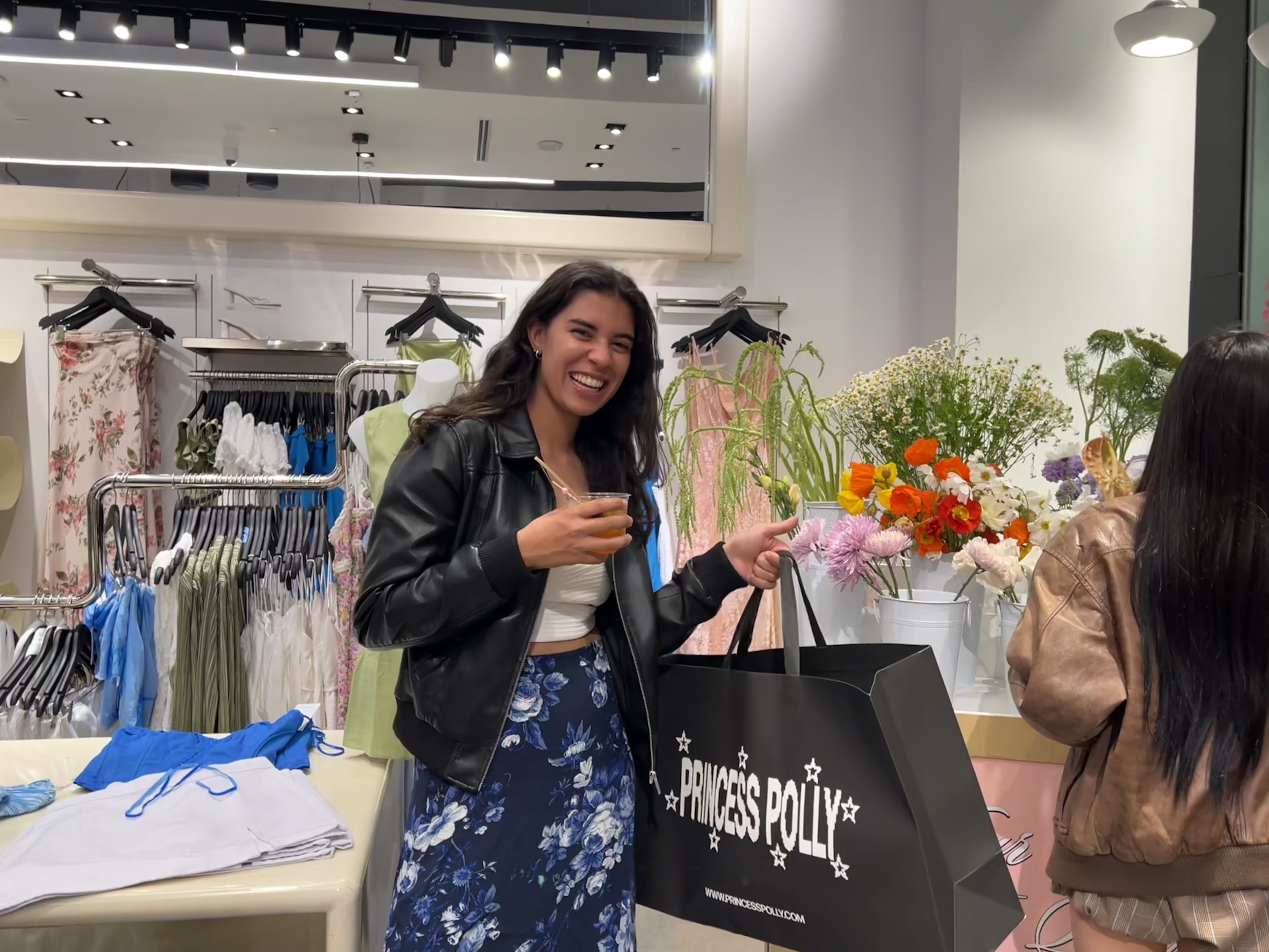 A smiling girl holds a shopping bag in a store.