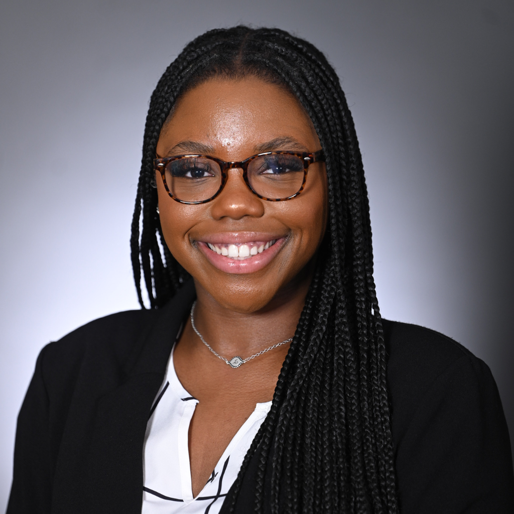 woman with dark braided hair posing in front of a gray background