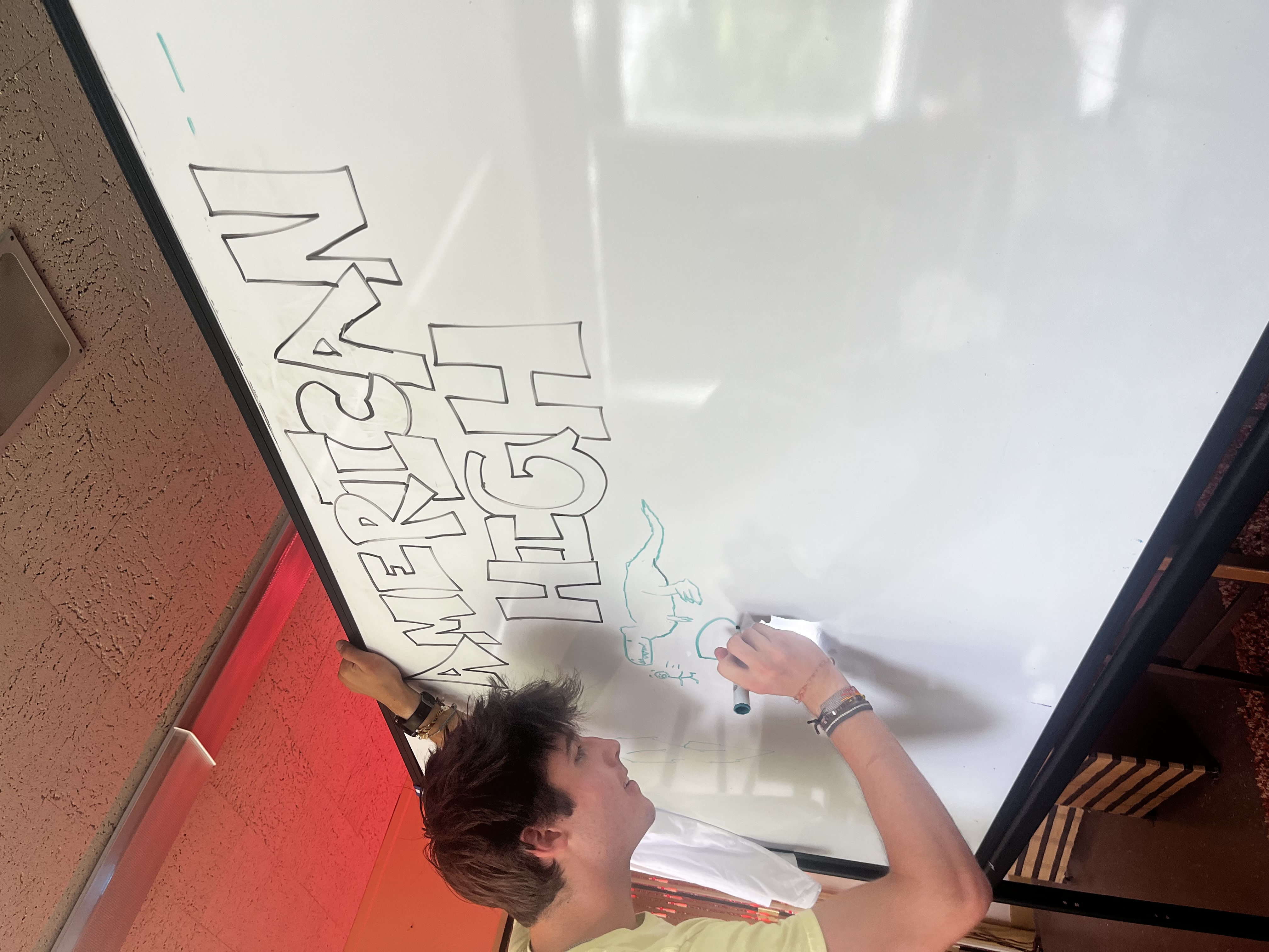 Boy writing American High on a Whiteboard