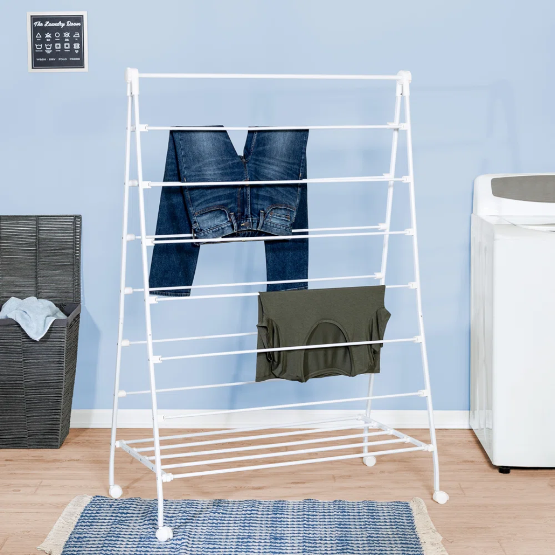 white metal clothing drying rack with jeans and a tank top draped over it