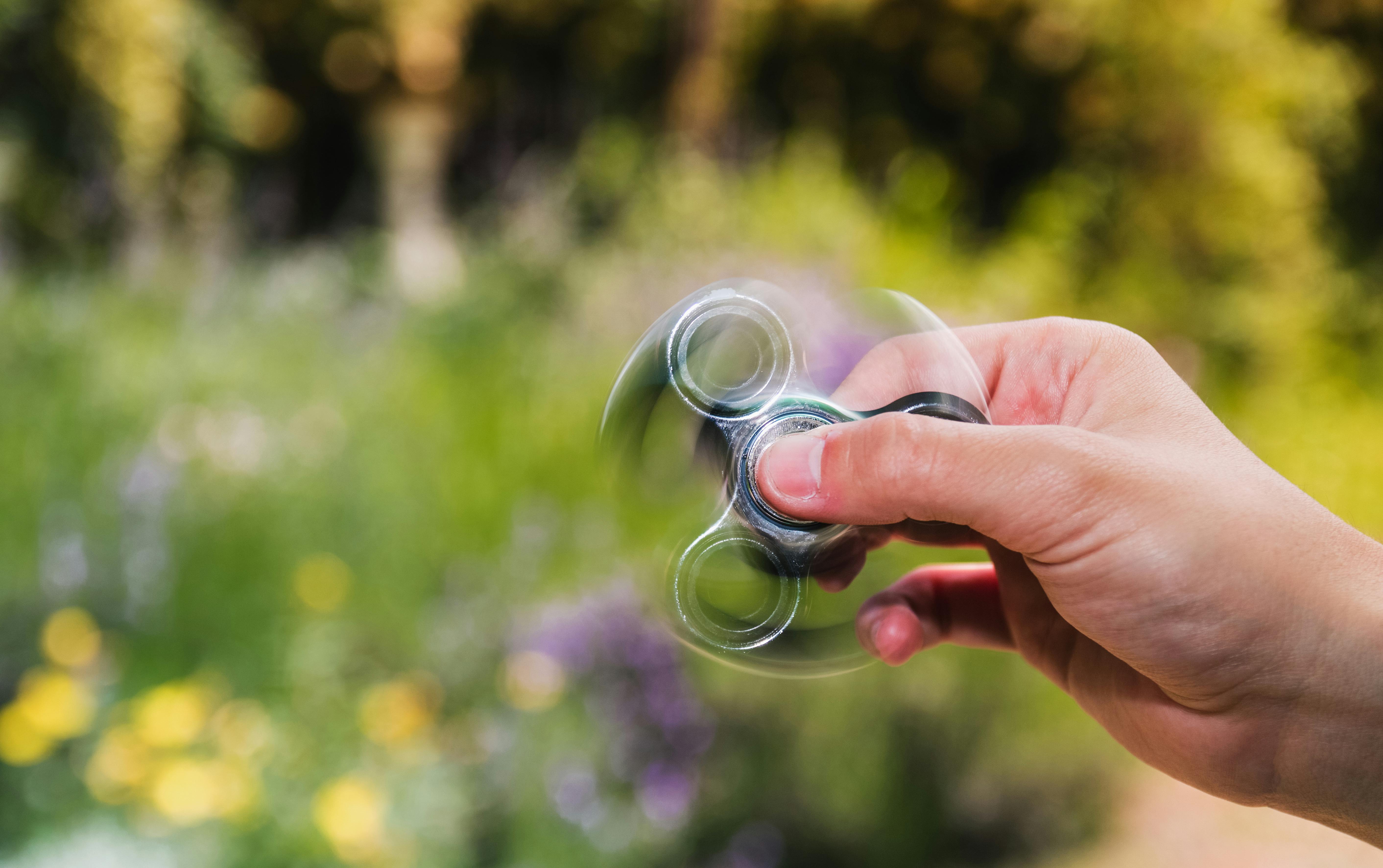 a fidget spinner being spun in front of flowers and grass