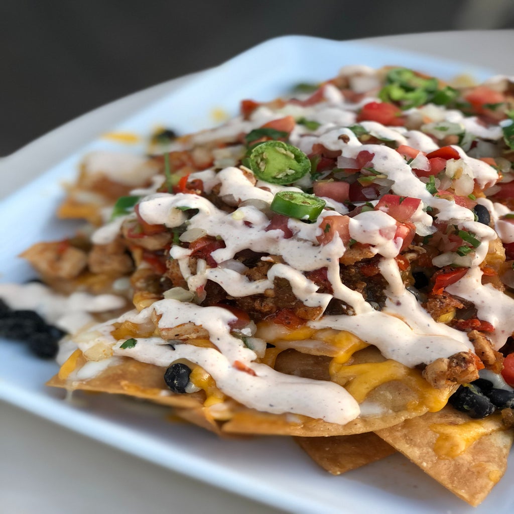 Plate of nachos covered in cheese and toppings