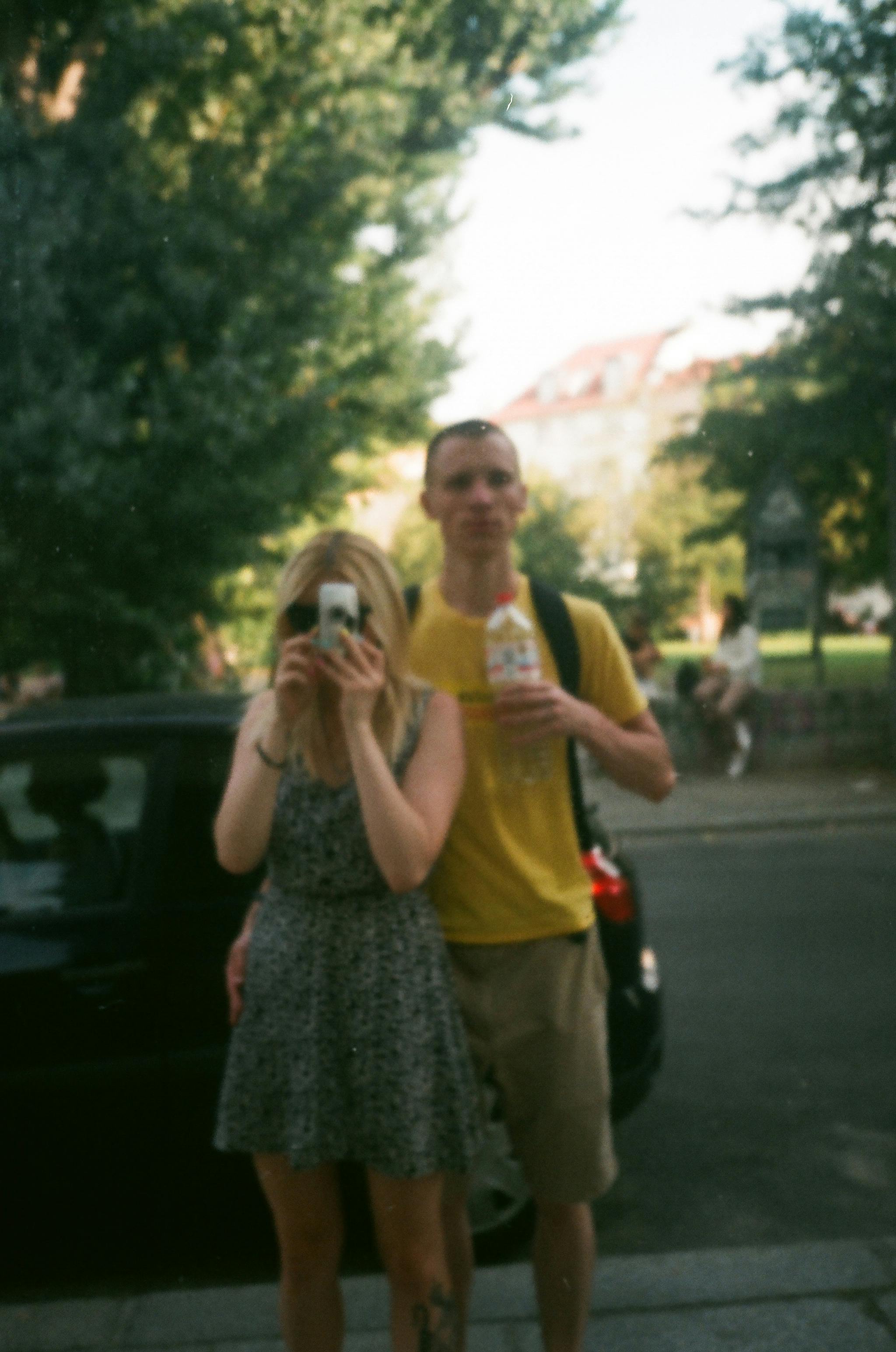 a couple taking a photo in a mirror like window on a building